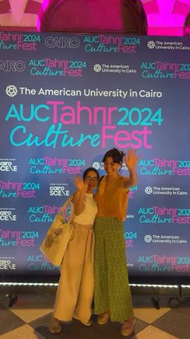 Two girls standing and smiling. Backdrop text: ϲͼ Tahrir CultureFest 2024