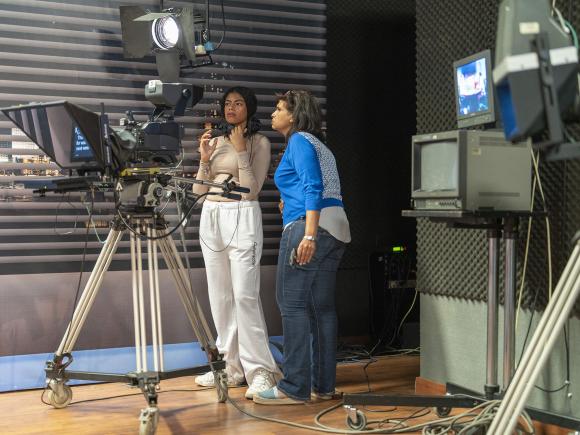 Two woman standing by a camera shooting an interview on ϲͼ News